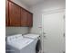 Laundry room with white appliances, brown cabinets, and a white door at 2597 E Hickory St, Gilbert, AZ 85298
