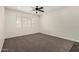 Cozy bedroom featuring plush carpeting, a ceiling fan, and a bright window at 26956 N 83Rd Gln, Peoria, AZ 85383