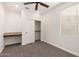 This bedroom features neutral carpet, a ceiling fan, a built-in desk, and a closet at 26956 N 83Rd Gln, Peoria, AZ 85383