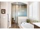 Bright bathroom features a soaking tub, a glass-enclosed shower with decorative tile, and plantation shutters at 31108 N 122Nd Ln, Peoria, AZ 85383