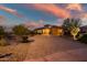 Beautiful front exterior of a home with lush landscaping, a paver driveway, and warm lighting under a colorful sky at 31108 N 122Nd Ln, Peoria, AZ 85383