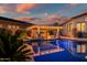 A beautiful pool features an attached pergola with a stone bar and seating area, reflecting the colorful evening sky above at 31108 N 122Nd Ln, Peoria, AZ 85383