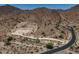 A vacant desert lot, outlined in white, alongside a curved road in a mountainous area at 3284 W Highlands Dr, Buckeye, AZ 85396
