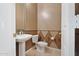 Elegant powder room with pedestal sink, toilet, and decorative wallpaper detail at 40123 N Majesty Trl, Anthem, AZ 85086