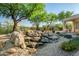 Picturesque backyard rock water feature with lush landscaping and desert trees at 40123 N Majesty Trl, Anthem, AZ 85086