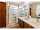 Bright bathroom features double sinks, framed mirrors, wood cabinets, and a glass enclosed shower at 4245 E Ficus Way, Gilbert, AZ 85298