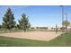Sand volleyball court surrounded by green grass and mature trees in a community park at 4266 E Blue Sage Ct, Gilbert, AZ 85297