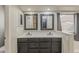 Modern bathroom features a double vanity with sleek mirrors and natural light from the window at 43727 W Wade Dr, Maricopa, AZ 85138