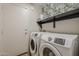 Modern laundry room with updated washer and dryer, shelf and a neutral paint at 43727 W Wade Dr, Maricopa, AZ 85138