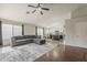 Open-concept living space with hardwood floors, gray sectional sofa, and view into modern kitchen at 43727 W Wade Dr, Maricopa, AZ 85138