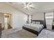 Serene main bedroom featuring a comfortable bed, ceiling fan, and view into the ensuite bathroom at 43727 W Wade Dr, Maricopa, AZ 85138