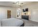 Main bedroom featuring a bed, ceiling fan, TV, dresser with lamps, and access to a walk-in closet at 43727 W Wade Dr, Maricopa, AZ 85138