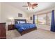 Cozy bedroom with a wood framed bed, carpeted floors, ceiling fan and natural light from window at 45539 W Long Way, Maricopa, AZ 85139