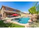 Inviting backyard pool area with a rock waterfall feature, patio, outdoor dining, and lush landscaping at 45539 W Long Way, Maricopa, AZ 85139