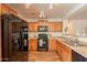 Modern kitchen with wood cabinets, granite countertops, and black appliances at 4642 E Sierrita Rd, San Tan Valley, AZ 85143