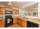 Well-lit kitchen with wood cabinets, black appliances, and a view into the living room at 4642 E Sierrita Rd, San Tan Valley, AZ 85143