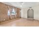 Bright living room features a brick accent wall, tile flooring, and a ceiling fan at 6430 W Thomas Rd, Phoenix, AZ 85033