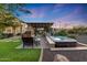 Beautiful backyard showcasing an outdoor kitchen, fireplace, covered patio, hot tub, and lush landscaping at 7230 W Pershing Ave, Peoria, AZ 85381
