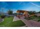 Backyard includes covered kitchen, fireplace, patio, seating, and manicured grass at 7230 W Pershing Ave, Peoria, AZ 85381