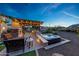 Outdoor fireplace, kitchen, and hot tub with brick-paved patio in landscaped backyard at 7230 W Pershing Ave, Peoria, AZ 85381