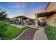 An inviting backyard with an outdoor kitchen, covered patio, fireplace, and well-manicured landscaping at 7230 W Pershing Ave, Peoria, AZ 85381