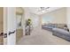 Carpeted living room showcasing a gray sectional couch, TV stand, and bright natural light at 7230 W Pershing Ave, Peoria, AZ 85381