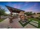 Inviting outdoor living space with a stone fireplace, a built-in BBQ, pergola, and comfortable seating at 7230 W Pershing Ave, Peoria, AZ 85381