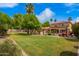 Sprawling backyard with lush green grass, mature trees, a sparkling pool, and comfortable lounge chairs at 7236 W Electra Ln, Peoria, AZ 85383