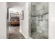 Tiled shower with glass door adjoins Primary bedroom with dark brown, four-poster bed frame and rustic decor at 7236 W Electra Ln, Peoria, AZ 85383