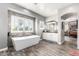 Bright bathroom features a modern tub, decorative tile accent wall, and a double vanity leading to the bedroom at 7236 W Electra Ln, Peoria, AZ 85383