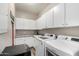 Well-organized laundry room featuring white cabinets, granite countertops, and modern washer and dryer at 7236 W Electra Ln, Peoria, AZ 85383