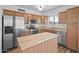 Light and bright kitchen showcasing stainless steel appliances, wood cabinets, and a center island at 724 N Pine St, Gilbert, AZ 85233