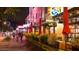 Nighttime view of a vibrant marketplace restaurant with outdoor seating, red umbrellas, and illuminated signage at 724 N Pine St, Gilbert, AZ 85233