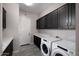 Well-organized laundry room features modern appliances and ample storage space in stylish black cabinets at 8040 E Jaeger St, Mesa, AZ 85207