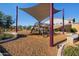 A playground with wood chip flooring, purple support beams and desert landscaping stands out in the desert sun at 8040 E Jaeger St, Mesa, AZ 85207