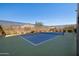 A fenced community tennis court with a blue and green surface sits in a desert residential area on a sunny day at 8040 E Jaeger St, Mesa, AZ 85207