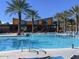 Resort-style community pool with palm trees, lounge chairs, and a modern clubhouse, offering a perfect retreat at 9230 E Scott Ave, Mesa, AZ 85212