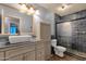 Well-lit bathroom with blue tiling, walk-in shower, toilet, and gray vanity at 11101 W Wilshire Dr, Avondale, AZ 85392