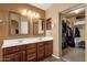 Bathroom featuring double vanity with wood cabinets and mirrors with a closet in the background at 11101 W Wilshire Dr, Avondale, AZ 85392