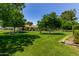View of lush green backyard with mature trees and manicured lawn at 12719 W Ashwood Dr, Sun City West, AZ 85375