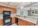 A well-lit kitchen with wooden cabinets, black appliances, and a view into an adjacent living space at 12719 W Ashwood Dr, Sun City West, AZ 85375