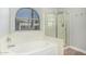 Bright bathroom featuring a soaking tub with a glass shower and a rounded window at 1343 W San Carlos Pl, Chandler, AZ 85248