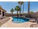 Backyard pool surrounded by palm trees, rock features, and ample space for relaxation at 1343 W San Carlos Pl, Chandler, AZ 85248