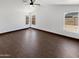 Primary bedroom featuring wood floors, a ceiling fan, and multiple windows for natural light at 15162 W Monroe St, Goodyear, AZ 85338