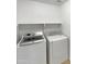 A bright laundry room featuring a front-load washer, a dryer, and a shelf at 15162 W Monroe St, Goodyear, AZ 85338