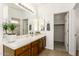 Bathroom features double sinks with wood cabinets, a large mirror, and access to a walk-in closet at 15674 W Mackenzie Dr, Goodyear, AZ 85395