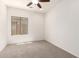 Neutral carpeted bedroom with a ceiling fan and a window at 15674 W Mackenzie Dr, Goodyear, AZ 85395
