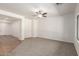Spacious living room with neutral carpet and a ceiling fan, bathed in natural light at 15674 W Mackenzie Dr, Goodyear, AZ 85395