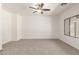 Bright living room featuring neutral carpet, a ceiling fan, and an abundance of natural light at 15674 W Mackenzie Dr, Goodyear, AZ 85395