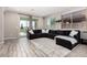 Spacious living room featuring modern wood-look flooring, a plush sectional sofa, and large windows for ample light at 17171 W Tonto St, Goodyear, AZ 85338